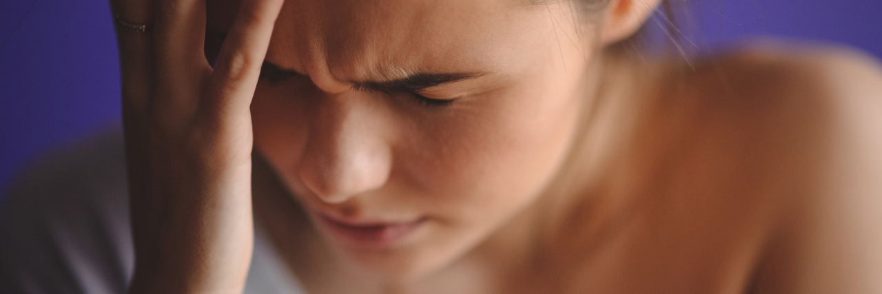 What It's Like to Fight for a Chronic Pain Diagnosis A woman holding her head in pain.
