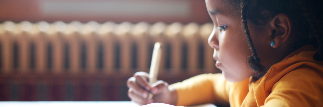 A young girl writing in a classroom