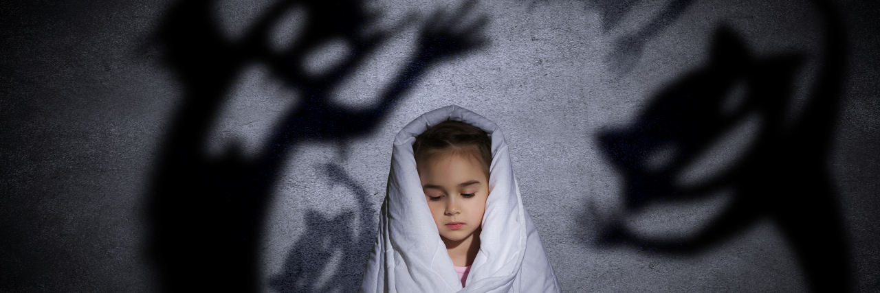 little girl hiding under blanket from monsters