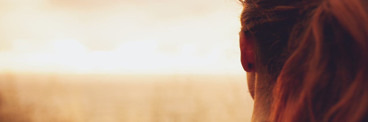 What to Remember If Chronic Illness Makes You Feel 'Less Than' woman looking at a sunset over a field