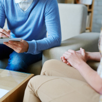 Psychologist making notes while listening to his patient