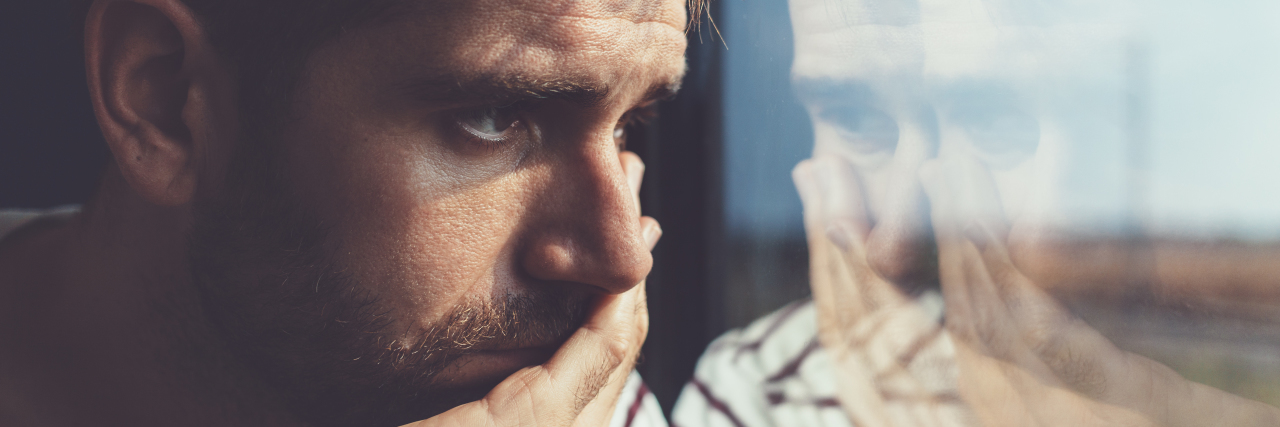 Post-Concussion Syndrome -- An Invisible Struggle Sad young man looking through window.