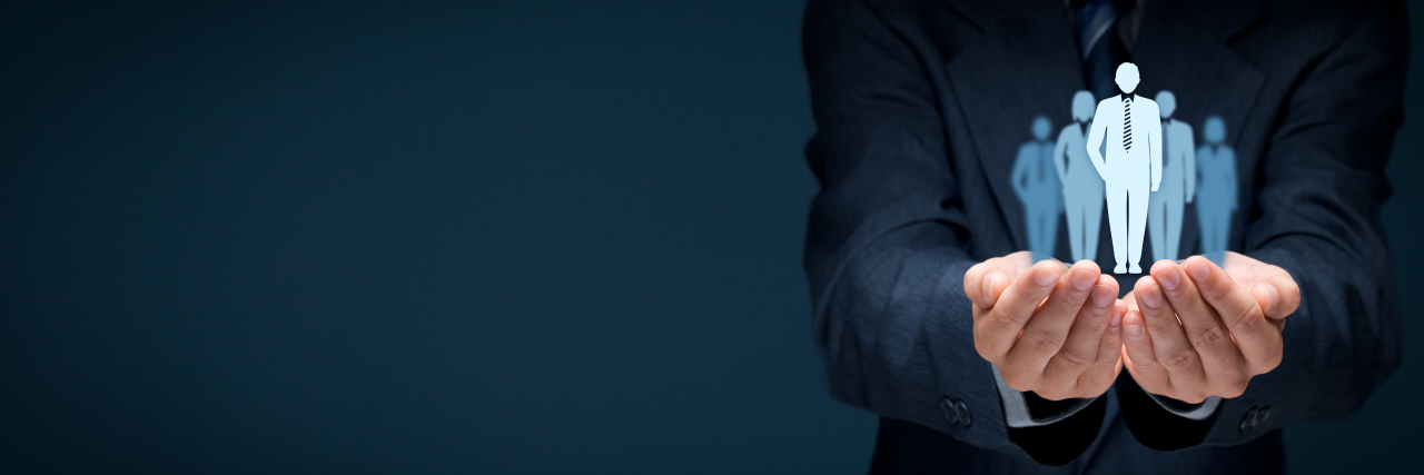 Medicaid Work Requirements Could Harm People With Autism Hands holding paper cutout figures in suits.