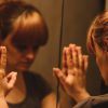 woman with her hands against the mirror looking at her reflection