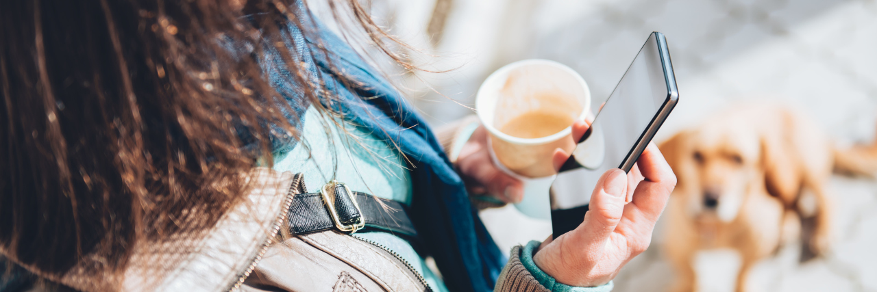 woman holding smartphone and coffee