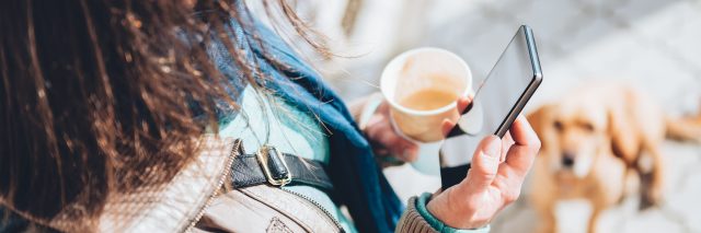 woman holding smartphone and coffee