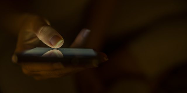 Close up of female hands using modern smartphone at home at night