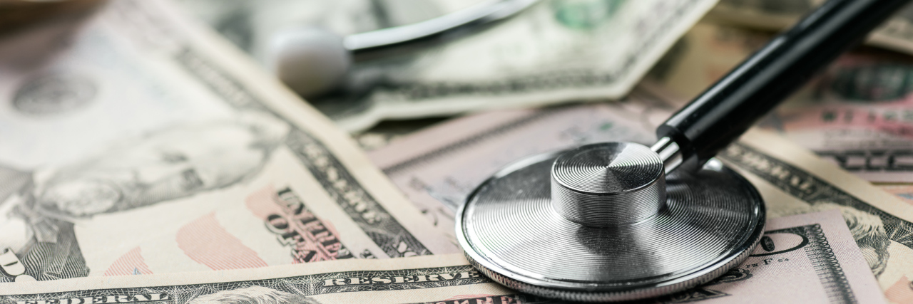 When You're Middle Class America Drowning in Healthcare Costs A stethoscope laying on a pile of cash.