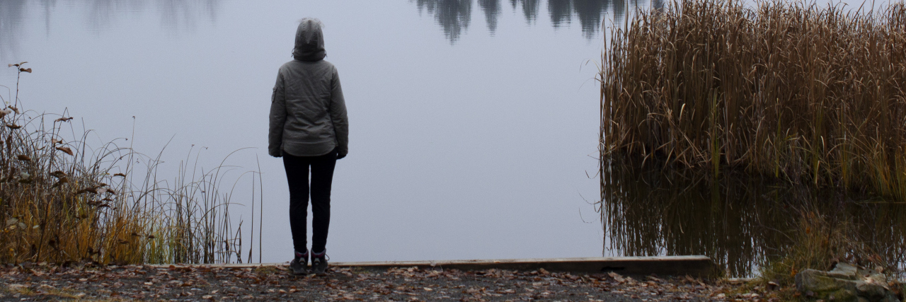 A person stands on the shore of Seeley Lake in northern British Columbia, Canada.
