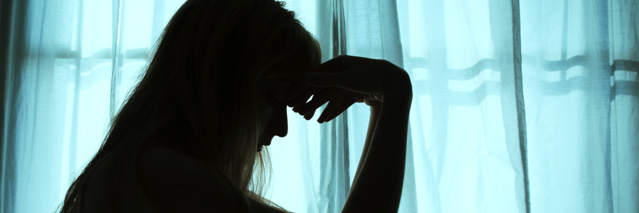 What Antidepressant Commercials Get Wrong About Depression Silhouette of woman sitting in bed by window