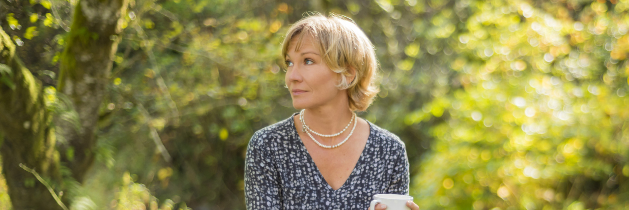 woman sitting outdoors and holding a teacup