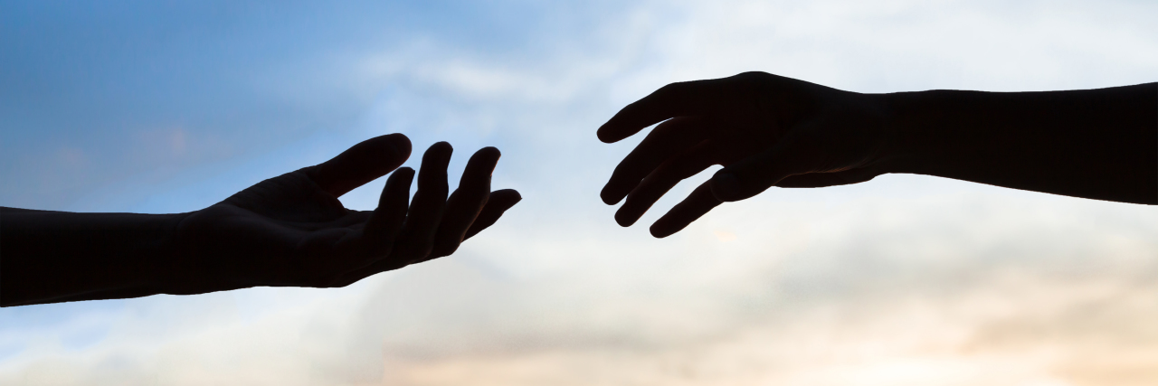 Asking for Help Is Hard With an Invisible Disability Two hands reaching to help each other, silhouette on sky background.