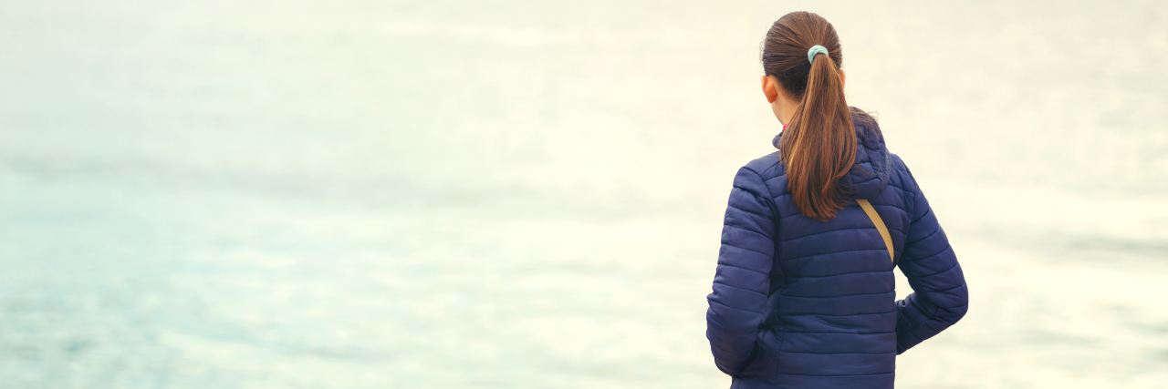 What It's Like to Have Achalasia Disorder as a Teenager Back view of one teenager girl thinking alone and watching the sea, winter or autumn day