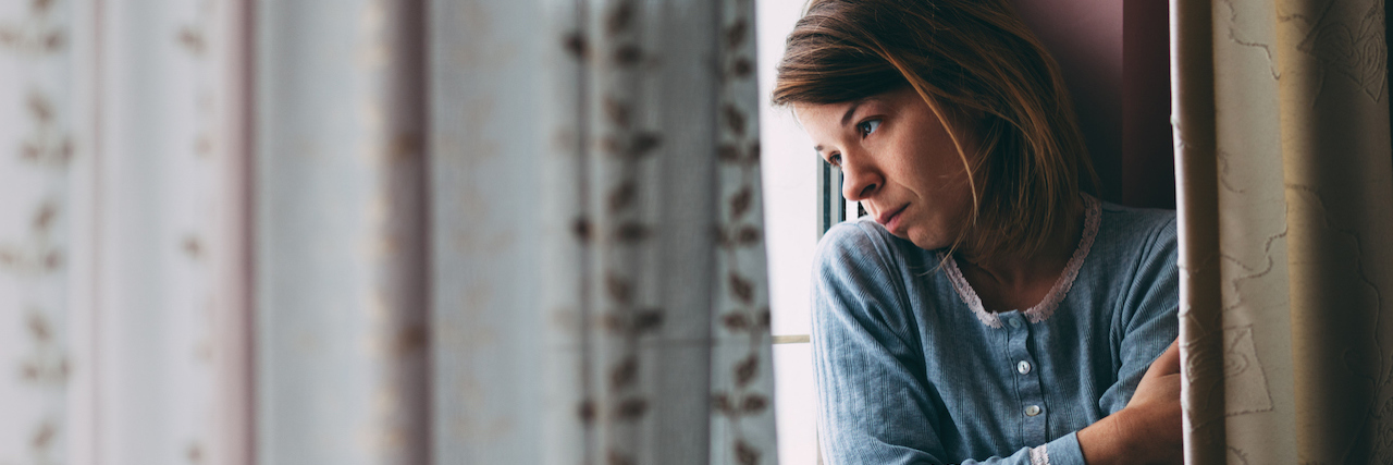 When Depression and Anxiety Come Back Young sad woman sitting on the window looking outside