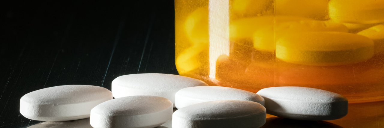 Researchers Create Compound for Non-Addictive Opioid Prescription bottle with blank label for copy space and white pills or tablets on metal table for opioid epidemic illustration