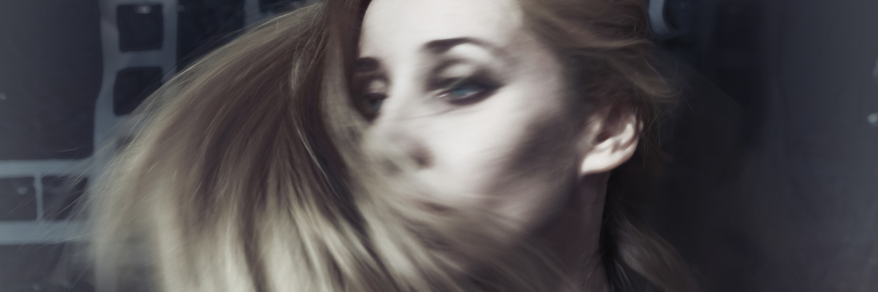 blurred motion of a blonde woman swishing her hair around her face