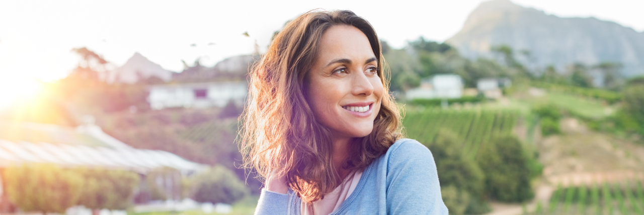 How I Treat My Bipolar Disorder and Found Stability Woman smiling and looking to the side outside in park