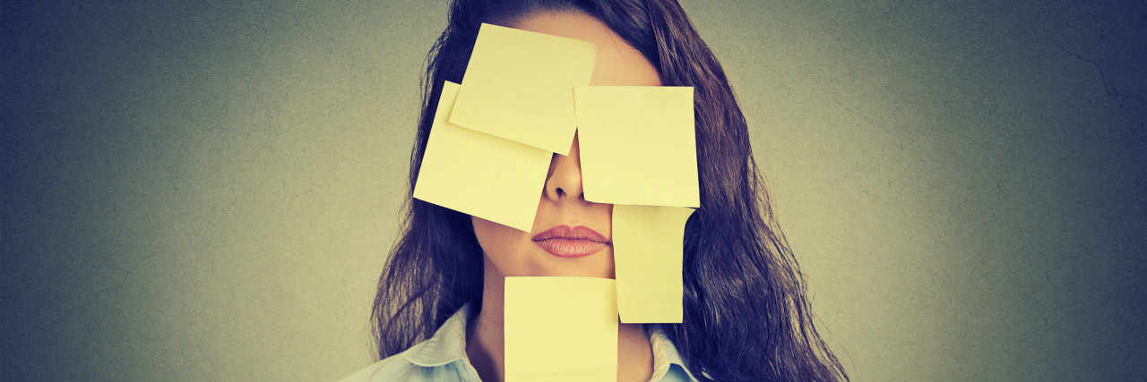 Why We Need to Look Past the Labels of Our Illnesses A woman wearing post-it notes on her face and shirt.