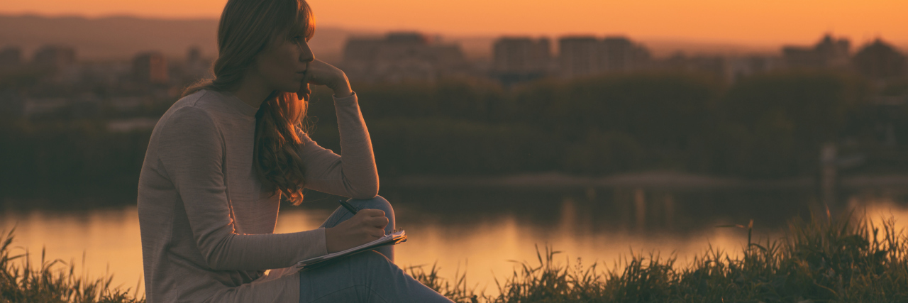 What My Abuser Grandfather’s Obituary Should Have Said sad woman sitting outside at sunset thinking and writing