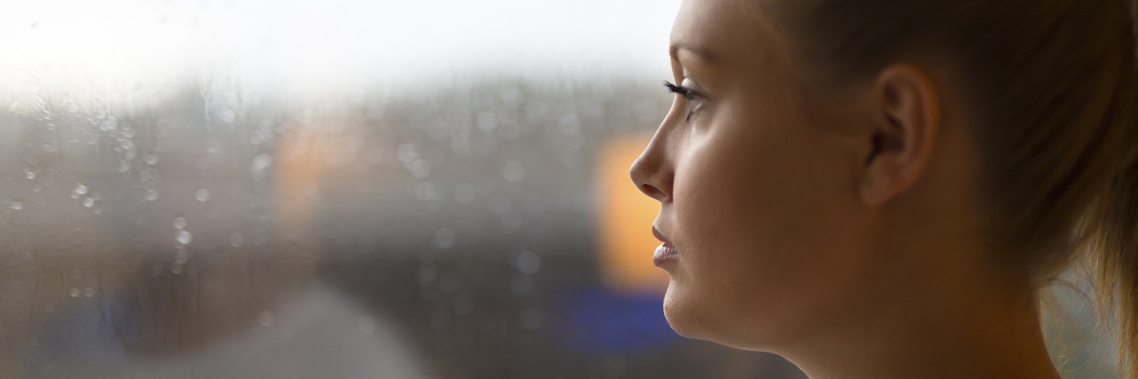 To My Family, From an Anxious Mom Thoughtful woman looks out the window home. Mental health and youth.