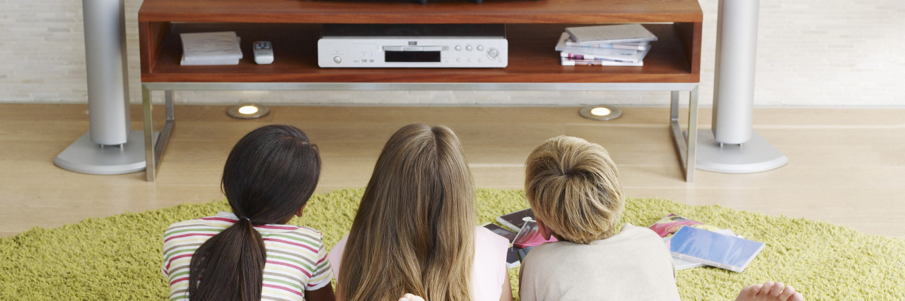 Three young kids watching television.