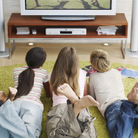 Three young kids watching television.