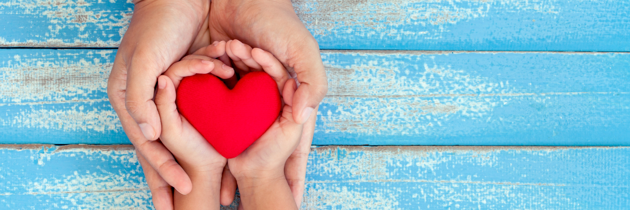 Raising Awareness for Multiple Sulfatase Deficiency Red heart in child kid and mother hands on old blue wooden table in vintage retro style