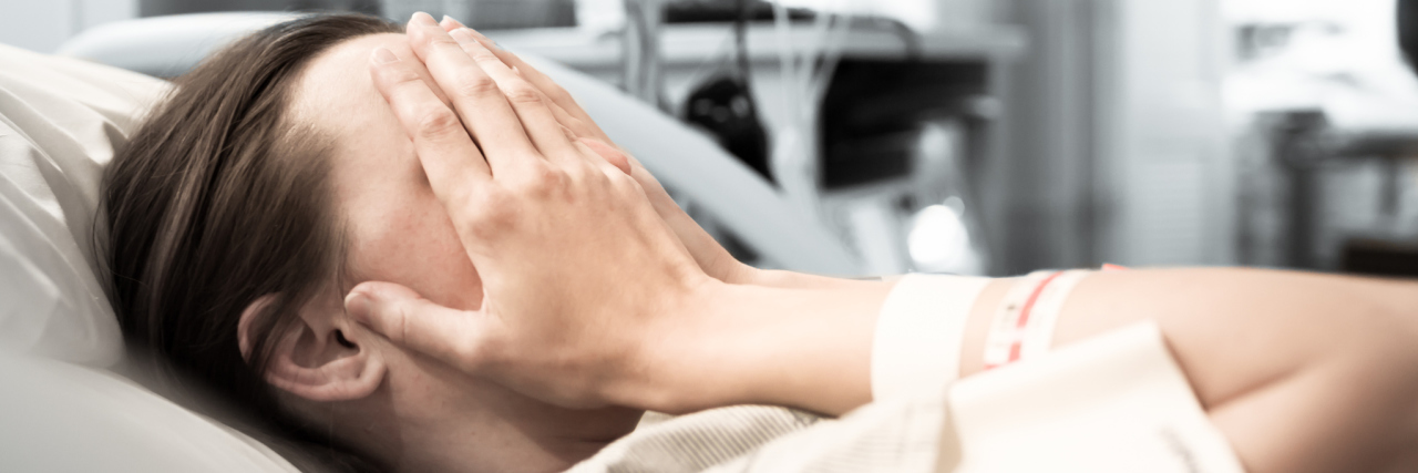 When Other Health Problems Affect Your Endometriosis A young woman laying in a hospital bed with her hands on her face.