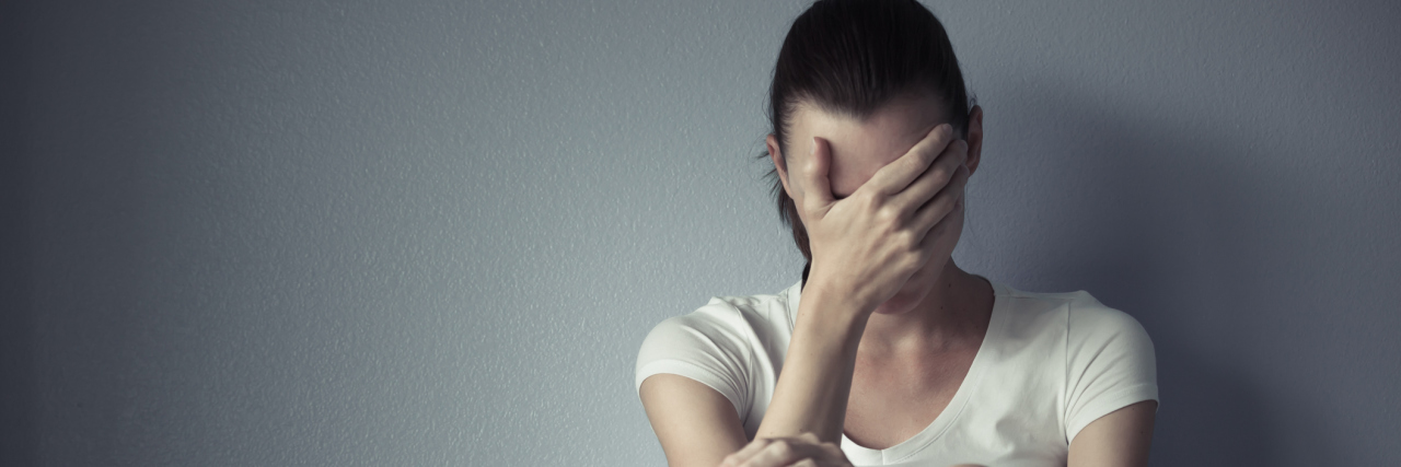 Sticking to New Year's Resolutions When You Are Chronically Ill A young woman sitting on the floor, overwhelmed.