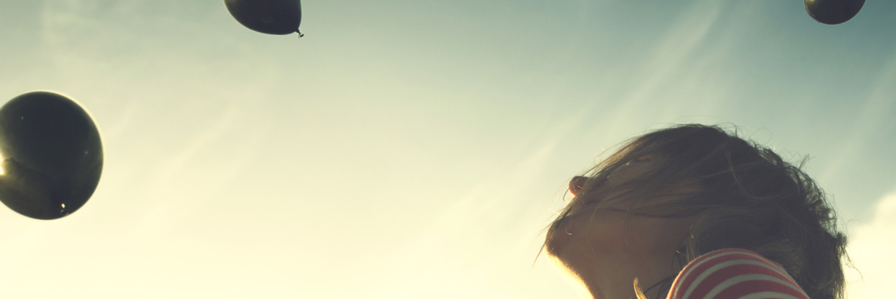 What It’s Like to Live With and Recover From Psychosis woman watching black balloons fall from sky in soft light