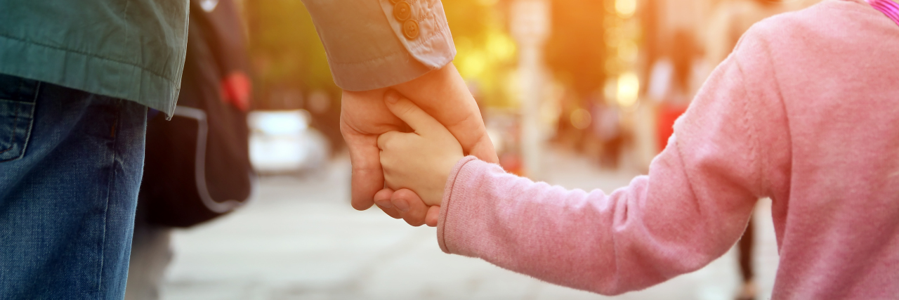 The Positives of Parenting a Child With Juvenile Myositis father holding the daughter/ child hand behind the traffic lights