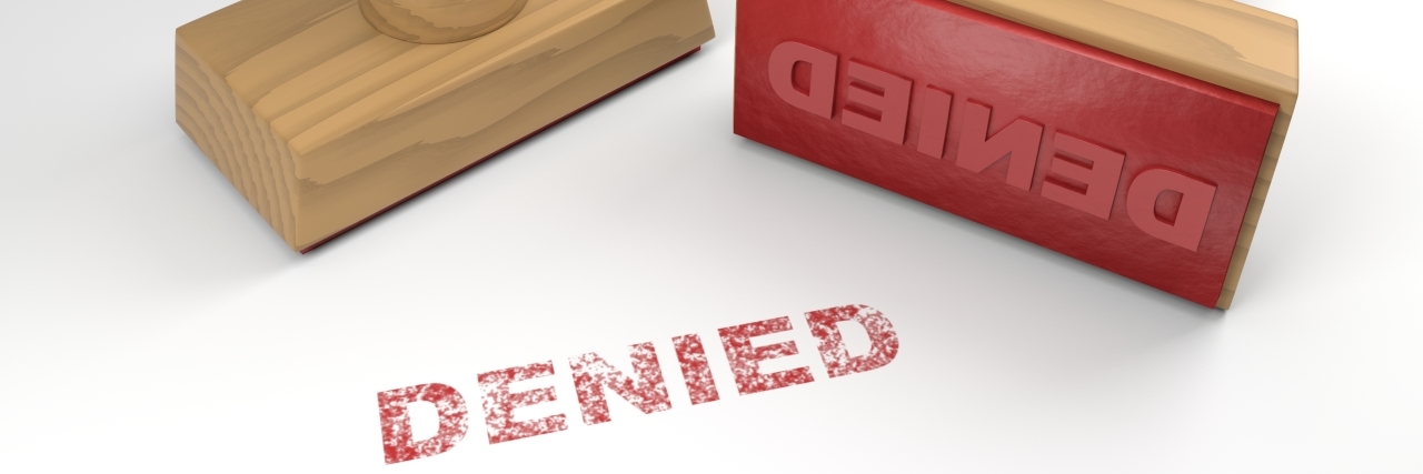 Denied Disability Benefits After the State Spied on Me Two rubber stamps with the word denied and a stamp on white background.