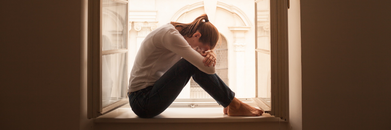 A woman hunched over, laying her head on her knees.