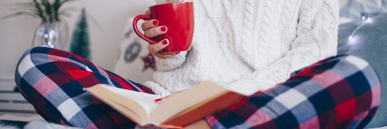 When I Was Told Audiobooks Were for 'People Too Lazy to Read' A woman holding a cup of coffee and reading a book in her pajama on the bed.