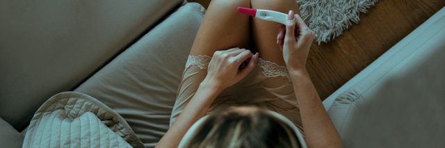 An attractive young woman is seen holding a negative pregnancy test.