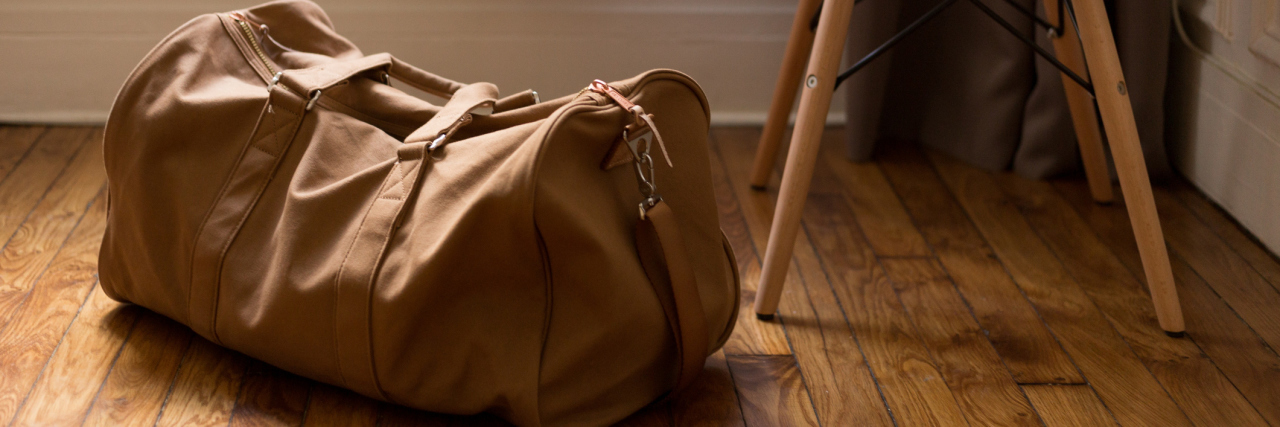 A duffle back by a white chair.