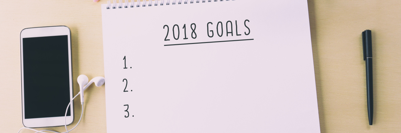 Making New Year's Resolutions With Complex Regional Pain Syndrome notepad saying "2018 goals" on a table with a pair of glasses and a glass of coffee
