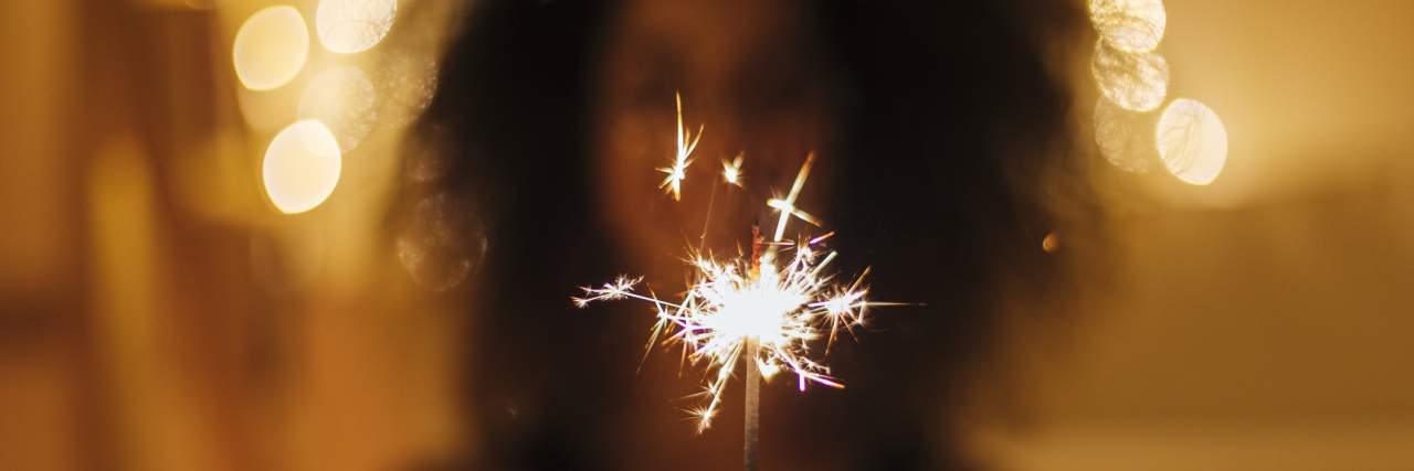 My New Year's Resolutions for Living With Fibromyalgia and Depression woman holding a sparkler