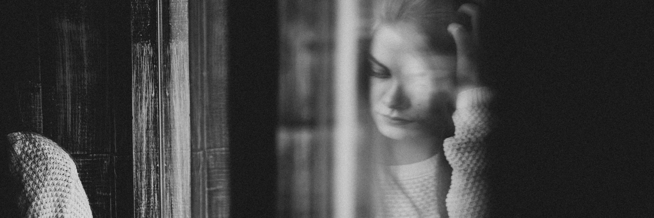black and white reflection of a girl reading on a window sill