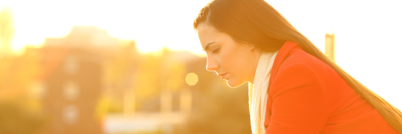 Fibromyalgia and New Year's Resolutions woman leaning against a balcony outside in the sunlight