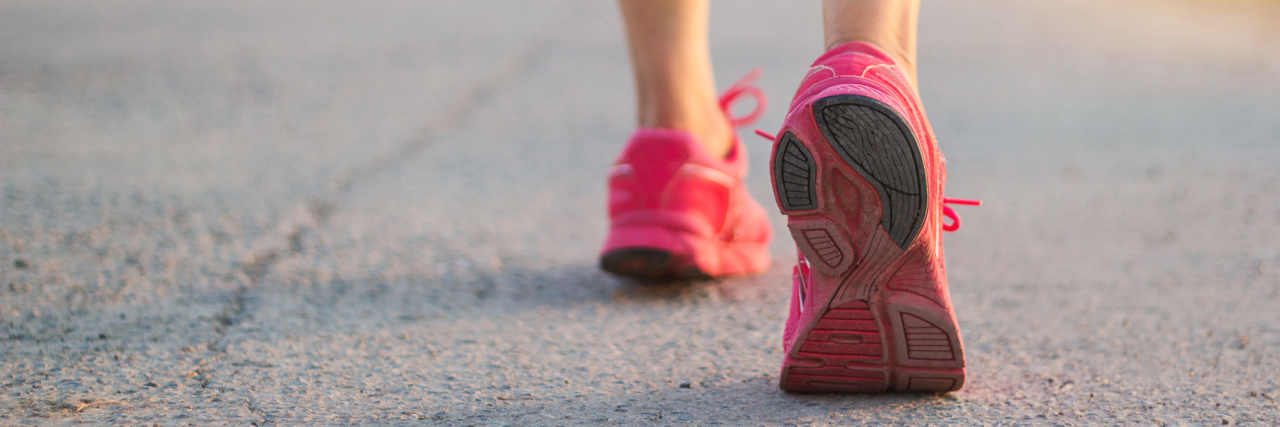 How I Learned to Embrace Exercise Despite Chronic Pain woman wearing sneakers and walking down a road