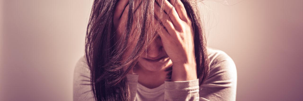 Why Bipolar Disorder Is Like Repeating the 5 Stages of Grief close up of woman alone with hands covering eyes