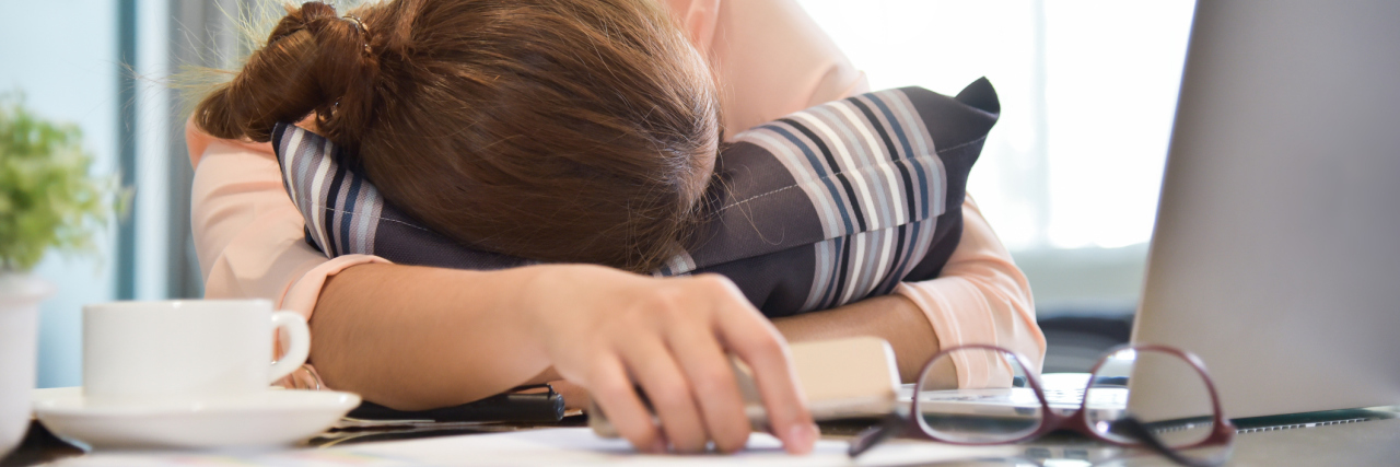 Dealing With Work Stress When You Have Fibromyalgia woman sleeping on her desk at work