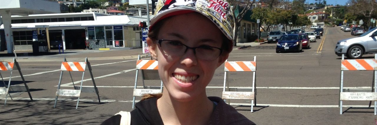 The Act of Kindness That Helped Me Thrive With Celiac Disease young woman wearing a hat and standing in a parking lot holding flowers