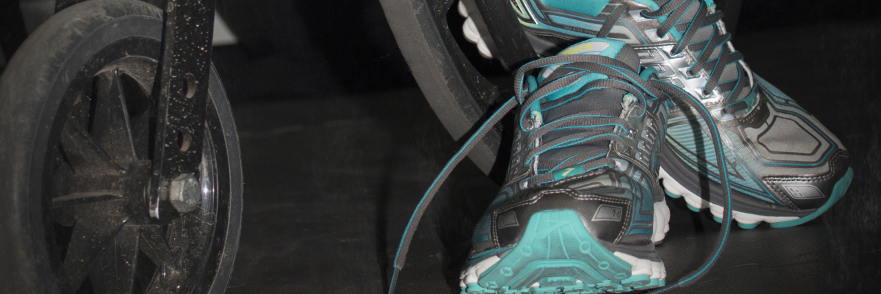 The Lyme Disease Recovery No One Prepares You For A pair of tennis shoes by a wheel of a wheelchair.