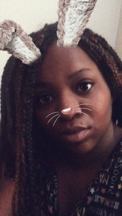 woman taking a selfie on snapchat with a filter of a bunny nose and ears overlaid