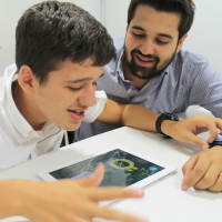 Zafer looks on as his brother uses the Otsimo app.