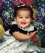 savannah as a toddler in a dress with balloons behind her
