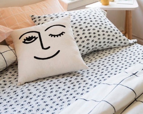 white throw pillow with winking face