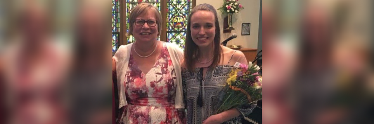 two women wearing dresses and stained in a church holding flowers